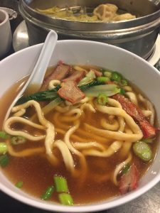half-eaten bowl of noodles with roast pork soup